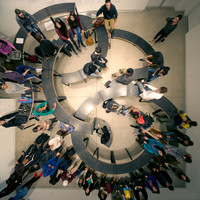 A bird's-eye view of furniture arranged in a figure-eight-like configuration with many people sitting on it.