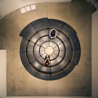 A bird's eye view of the Adrian Blackwell's Furnishing Positions sculpture configured to resemble a fully circular amphitheatre with two people sitting on it facing each other.