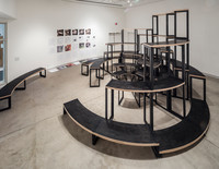 Adrian Blackwell's sixth configuration of furniture is centered in the space, with curved pieces of furniture at various heights in a semi-circular formation. A collection of broadsheets are installed along the back wall.